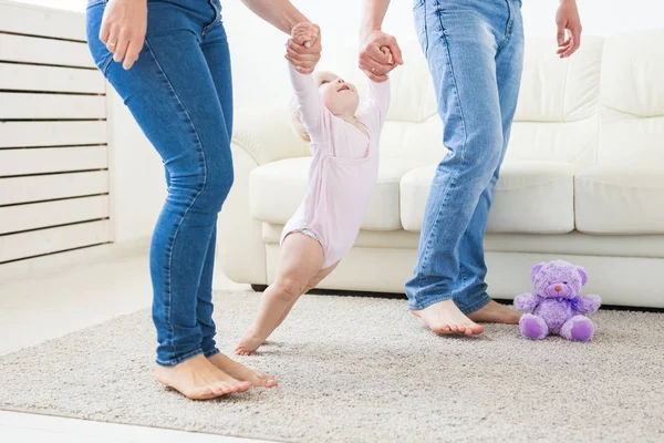 Маленька дівчинка перші кроки за допомогою мами і тата — стокове фото