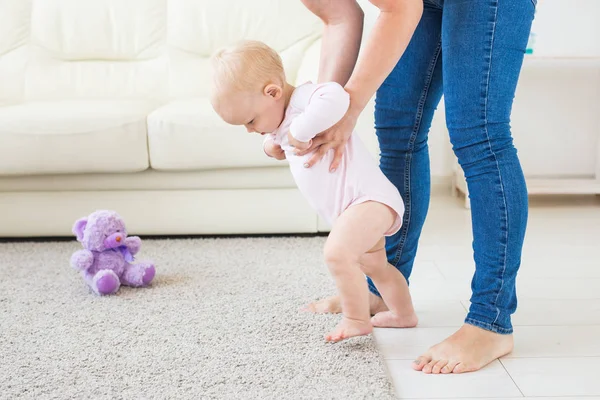 Die ersten Schritte des Kleinkindes, das im weißen, sonnigen Wohnzimmer laufen lernt. Schuhe für Kinder. — Stockfoto