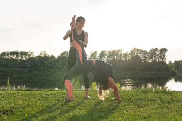 Female friends enjoying relaxing yoga outdoors in the park.