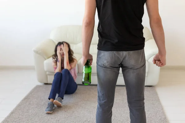 Domestic violence, alcoholic and abuse concept - drunk man with bottle abusing his wife lying on the floor — Stock Photo, Image