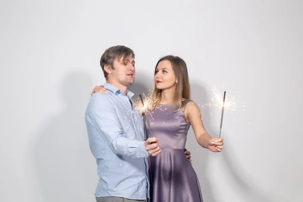 Párty, Rodina, Vánoce, nový rok a prázdniny-zábavný pár, který drží sparklery na bílém pozadí — Stock fotografie