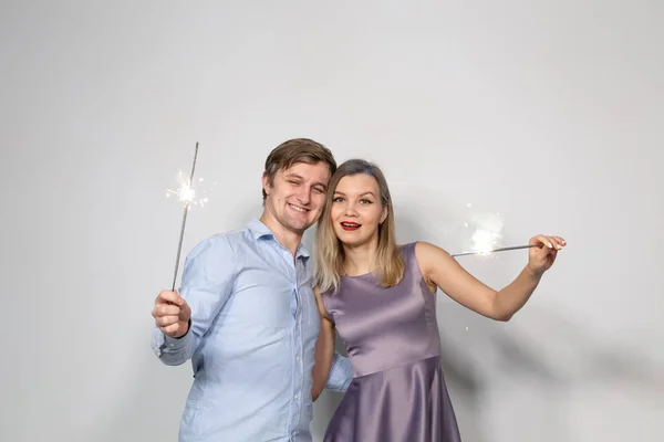 Festa, Natal, Ano Novo e feriados conceito - jovem casal segurando sparklers no fundo branco — Fotografia de Stock