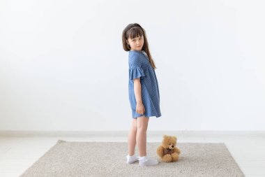 Beyaz odada oyuncak ile mavi elbiseli çocuk kız