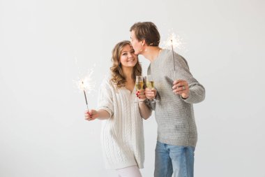 Yeni yıl, tatiller, tarih ve sevgililer günü konsepti - Beyaz arka plan üzerinde kıvılcımLar ışık ve şampanya bardak tutan Loving çift