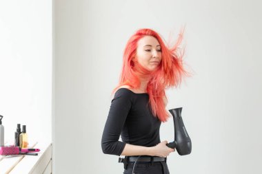 Stilist, moda, kuaför, insan kavramı - kadın onu renkli saç kurutma