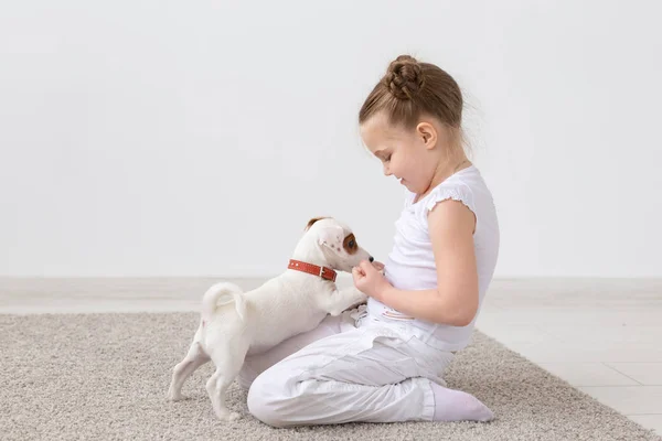 Concepto de perros, mascotas y niños - niña jugando en el suelo con un lindo cachorro — Foto de Stock