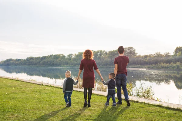 Elternschaft und Naturkonzept -Familie aus Mutter und Vater mit zwei Jungen Zwillingskinder in einem Park im Sommer an einem Fluss bei sonnigem Tag — Stockfoto