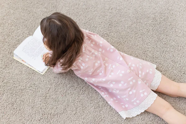 Mädchen liegt auf dem Boden und liest ein Buch. — Stockfoto