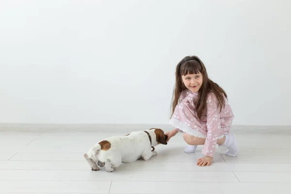 Mała dziewczynka w różowej sukni gra z jej pies Jack Russell Terrier — Zdjęcie stockowe