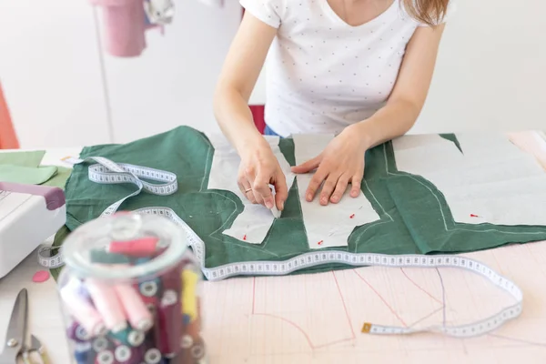 Las manos de una joven diseñadora hacen marcas para un nuevo producto de costura sentado en la mesa junto a la máquina de coser. Concepto de negocio creativo y diseño . — Foto de Stock