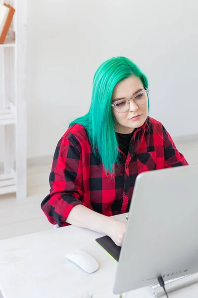 Creative, illustrator and designer concept - happy woman with green hair is drawing a project, vertical shot