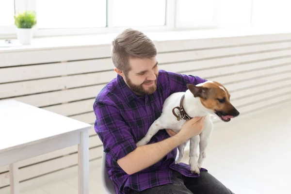 People, pets and home concept - young man playing with jack russell terrier puppy — Stock Photo, Image