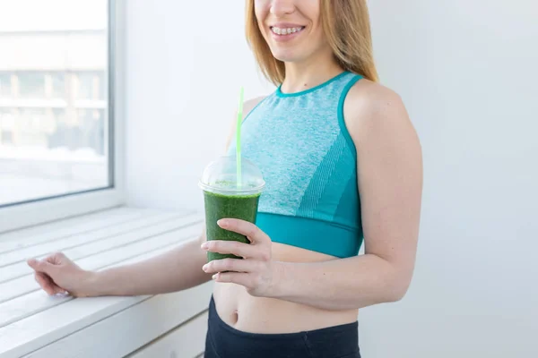 Healthy, sport, diet and people concept - Successful fitness urban woman recommending detox smoothie, close-up