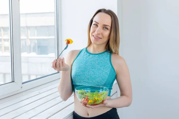 Zdrowy styl życia, fitness i dieta koncepcja-Sałatka dietetyczna i szczupła kobieta w sporcie nosić w pobliżu okna — Zdjęcie stockowe