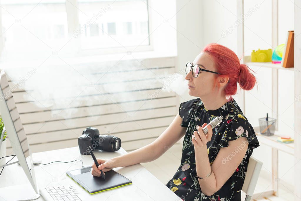 graphic designer concept - Female graphic designer working on computer while using graphic tablet at desk in the office and smoking a vape