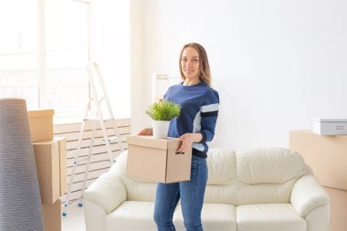 Büyüleyici genç bekar kadın onu gri lop kulaklı İskoç kedi yanında yeni bir dairede ayakta iken hareket ederken şeyler ile bir kutu tutar. Hareketli ve housewarming kavramı.