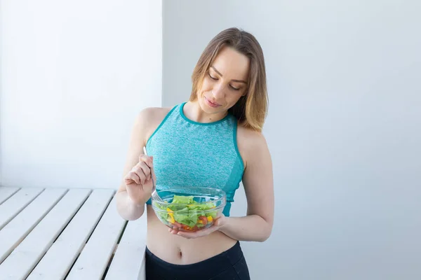 Stile di vita sano, fitness e dieta concetto - insalata dietetica e donna in abbigliamento sportivo — Foto Stock