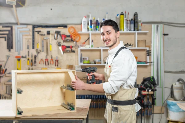 Fábrica de muebles, pequeñas empresas y concepto de personas - Trabajador joven trabaja en una fábrica para la producción de muebles —  Fotos de Stock