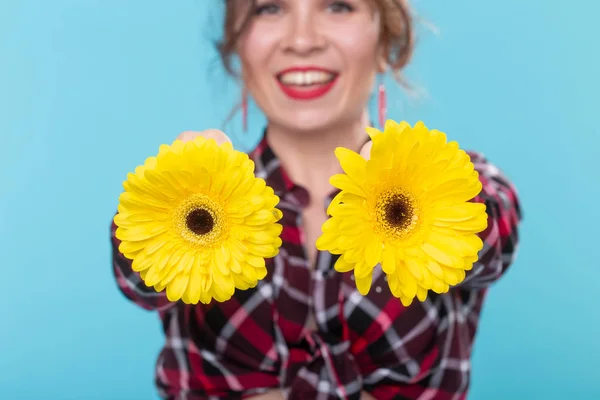 파란색 배경에 포즈 유방 근처 다른 마음과 두 개의 노란색 꽃을 들고 격자 무늬 셔츠에 긍정적 인 젊은 여성의 초상화. 모든 형태의 바디 뷰티의 개념, 몸 양성 — 스톡 사진