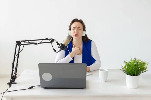 Concepto de presentador de radio - Mujer trabajando como presentadora de radio sentada frente al micrófono sobre fondo blanco en el estudio — Foto de Stock
