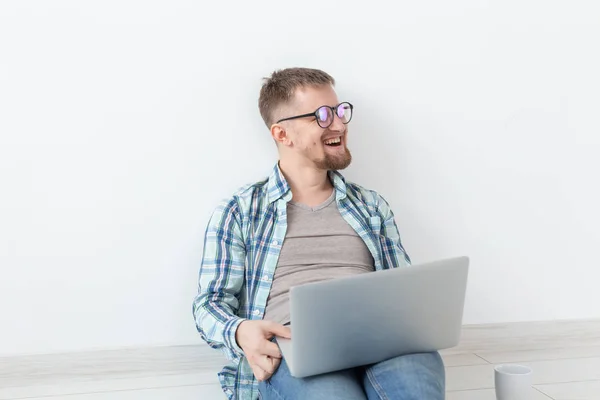 Kopya alanı ile boş bir odada yerde oturan yeni konut arayışı içinde gündelik giysiler içinde Pozitif genç adam internette sörf — Stok fotoğraf