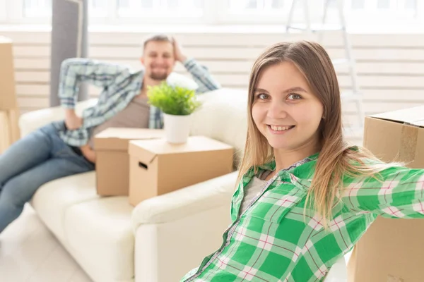 Jovem sorridente positiva sentada contra seu marido enevoado rindo em uma nova sala de estar enquanto se muda para uma nova casa. O conceito de alegria a partir da possibilidade de encontrar novas habitações . — Fotografia de Stock