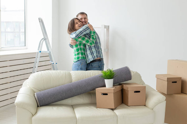 Young couple in denim pants embracing rejoicing in their new apartment during the move. The concept of housewarming and credit for new housing.