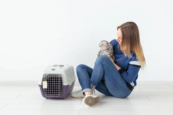 Encantadora joven positiva sostiene en sus manos a su hermoso gato escocés gris plegado sentado en el suelo en un nuevo apartamento. Concepto de mascota . — Foto de Stock