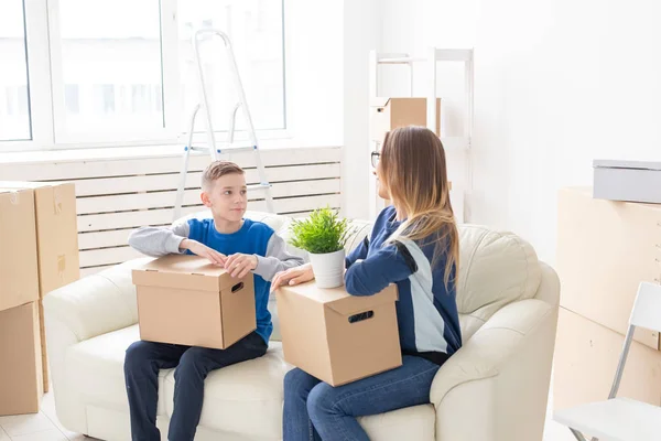 귀여운 싱글 엄마와 어린 소년 아들이 이동 후 물건을 상자를 정렬합니다. 주택 집안일의 개념과 새로운 주택의 기쁨. — 스톡 사진