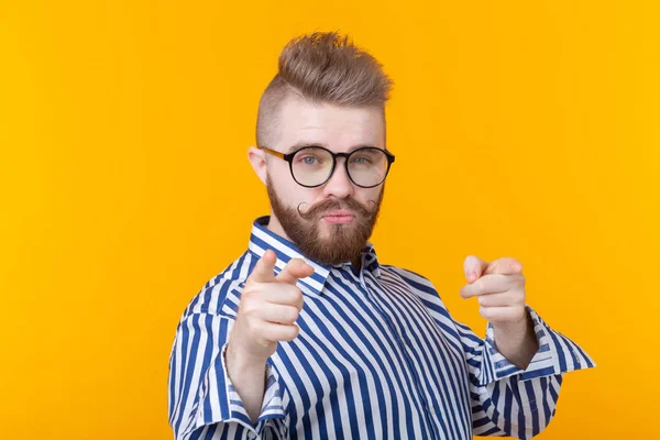 Un joven divertido con bigote y barba y gafas se muestra sobre un fondo amarillo. Concepto de publicidad no estándar . — Foto de Stock