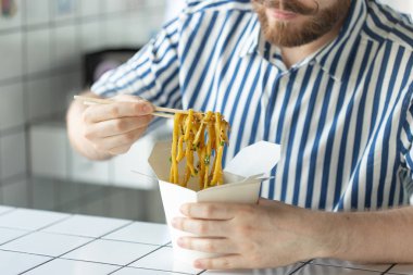 Yakın çekim bir gömlek genç kimliği belirsiz adam el ahşap sopalar çin erişte tutuyor. Lezzetli Asya mutfağı konsepti.