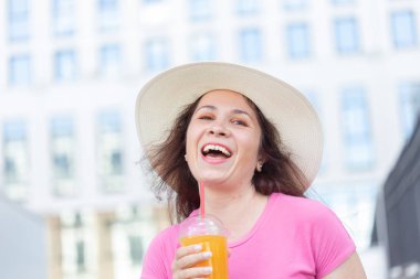 Sıcak bir yaz gününde suyu ile şehirde dolaşan bir şapka genç güzel neşeli kadının alt görünümü portre. Hafta sonu şehirde yürüme kavramı.