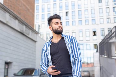 Sokakta cep telefonu ile Modern Arap genç adam. Dış mekan portresi.
