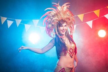 Karnaval, oryantal dans ve tatil konsepti - Altın kostüm giyen ve gülümseyen güzel kadın samba dansçısı
