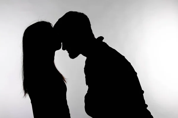 Una pareja caucásica hombre y mujer besándose en silueta de estudio aislado sobre fondo blanco . — Foto de Stock