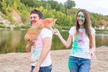 Festival holi, tatil, turizm, evde beslenen hayvan ve doğa kavramı - kadın ve erkek kedi ile portre çok renkli toz kaplı.