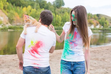 Festival holi, turizm ve doğa kavramı - kadın ve erkek kedi ile portre çok renkli toz kaplı.
