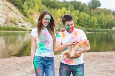 Evde beslenen hayvan, yaz turizm, festival holi ve doğa kavramı - komik erkek ve kadın ile kedi doğal zemin üzerine