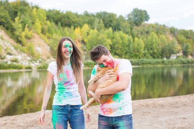 Festival holi, tatil, turizm, evde beslenen hayvan ve doğa kavramı - kadın ve erkek kedi ile portre çok renkli toz kaplı.