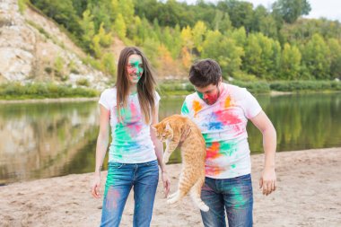 Festival holi, turizm ve doğa kavramı - kadın ve erkek kedi ile portre çok renkli toz kaplı.