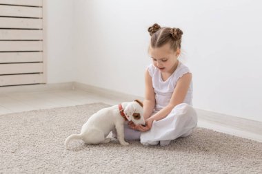 Çocuk, Evcil hayvanlar ve hayvanlar kavramı - küçük kız çocuk pijama ile Jack Russell Terrier köpek yavrusu yerde oynamak
