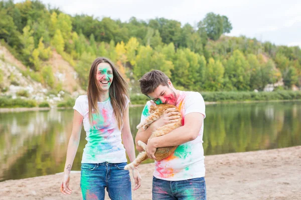 축제 holi, 휴일, 관광, 애완 동물 및 자연 개념-여자와 고양이 함께 남자의 초상화 덮여 멀티 컬러 먼지 — 스톡 사진