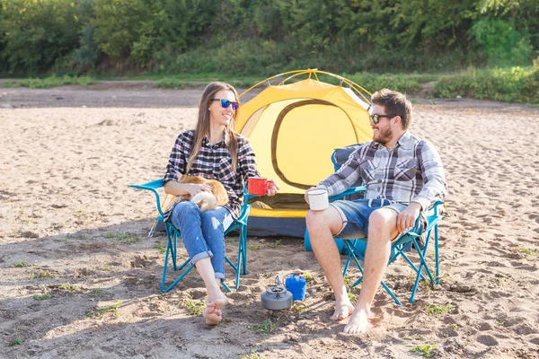 Personas, el turismo de verano y el concepto de la naturaleza - pareja joven beber té cerca de la tienda —  Fotos de Stock