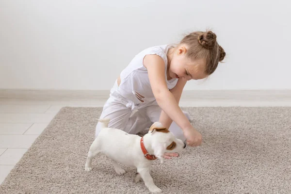Kisállat, a gyermekkor és az állatok koncepció - kisgyermek lány játszik a padlón Jack Russell Terrier kiskutya — Stock Fotó