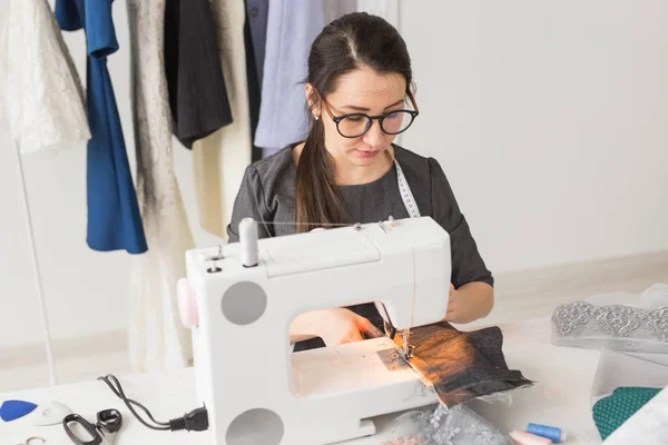 Люди и концепция моды - молодая портниха шьет одежду на швейной машинке — стоковое фото