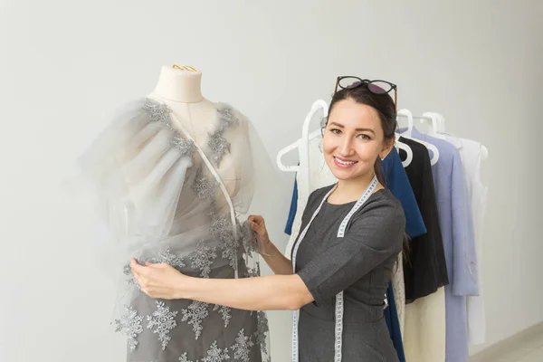 Dressmaker, fashion designer, tailor and people concept - young woman fashion designer in her showroom