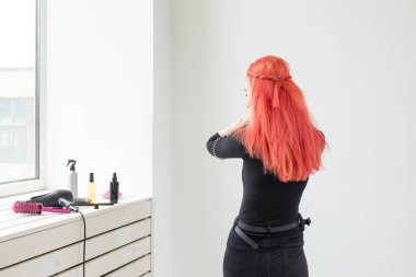 Genç ve güzel bir kadın oturma odasında saçını tarıyor.