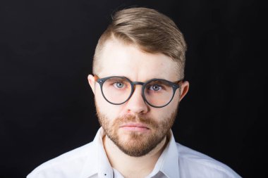 Siyah duvara karşı duran şık gözlüklü portre yakışıklı sakallı adam kapatın