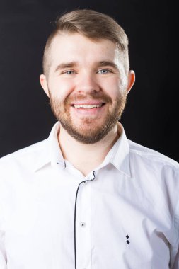 Siyah arka plan üzerinde mutlu gülen genç sakallı adam portresi