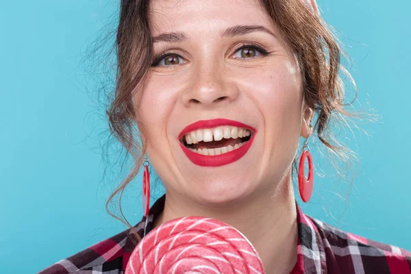 Dieta, postre y comida chatarra: estilo pin-up de mujer de primer plano con piruleta sobre el espacio de copia de fondo azul . — Foto de Stock